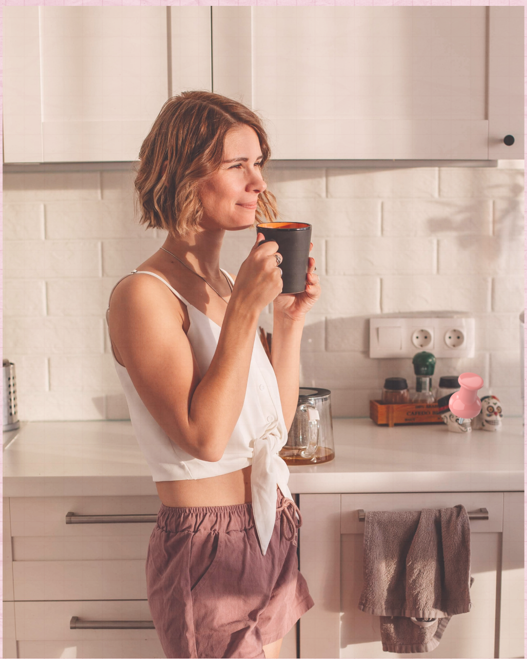 Woman holding a warm mug in a softly lit kitchen during a quiet morning moment